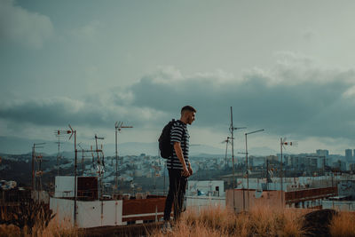 Full length of man standing on field against cityscape