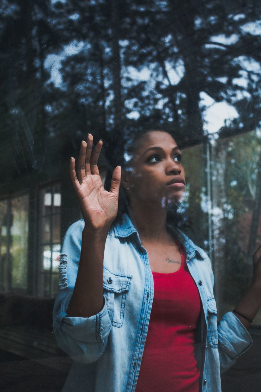 one person, real people, front view, young adult, tree, casual clothing, standing, waist up, looking, lifestyles, hand, gesturing, young women, focus on foreground, looking away, leisure activity, women, looking up, adult, outdoors, hairstyle, hand raised