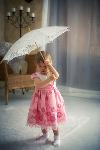 Cute girl standing against pink umbrella