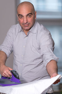 Portrait of man ironing clothes at home