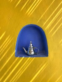 Close-up of tea kettle in niche on yellow wall