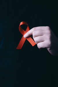 Close-up of person holding umbrella against black background