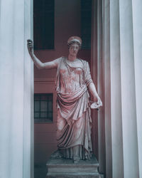 Statue of man standing by window of building