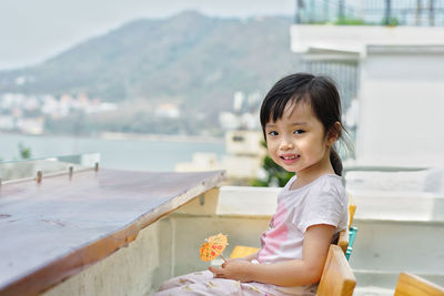 Portrait of young woman sitting on retaining wall