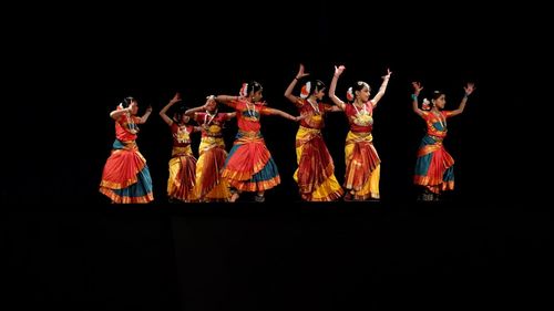 Group of people dancing against black background