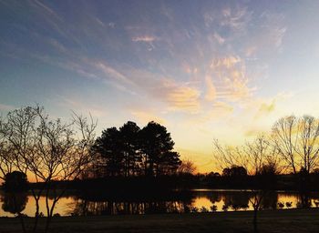 Silhouette trees by lake against sky during sunset