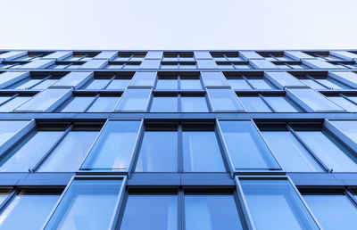 Blue glass and steel front of a downtown office building shot bottom-up before a clear blue sky