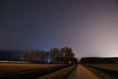 Road amidst trees against sky at night