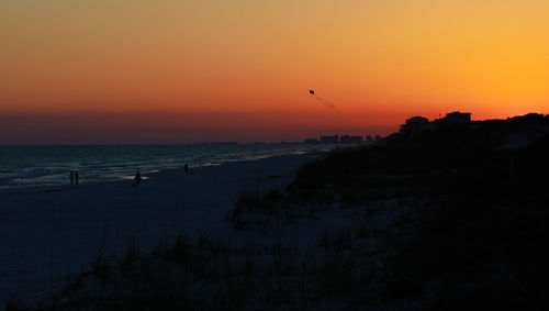 Flying a kite on the beach in florida while the sky is orange from the beautiful sunset