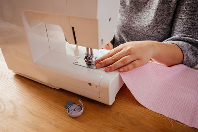 Midsection of woman using sewing machine