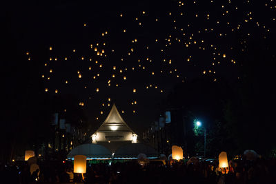 Illuminated lanterns in city against sky at night