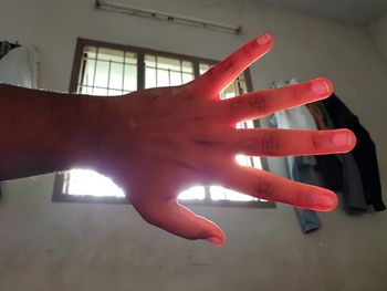 Close-up of hand on red wall