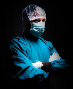 Midsection of person wearing mask against black background