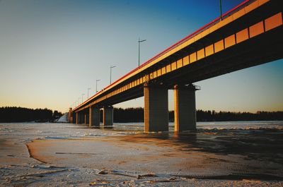 Bridge over road against clear sky during sunset