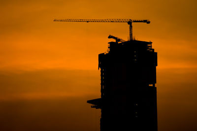 Silhouette of tower against orange sky