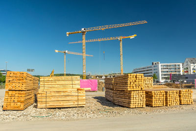 Stack of crane by building against clear blue sky