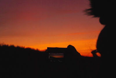 Silhouette person holding orange sky during sunset