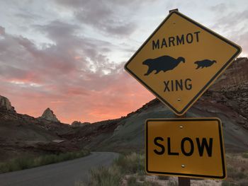 Road sign against sky at sunset