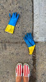 Low section of person standing with discarded gloves on the street