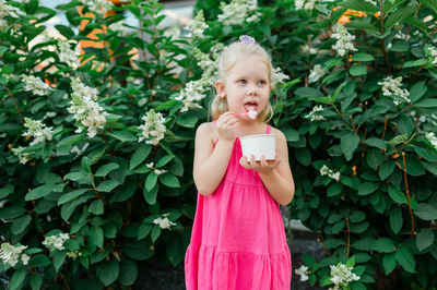 Portrait of young woman standing against plants