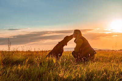 Mature woman and her beautiful hungarian vizsla. dog love background. woman kissing her dog.