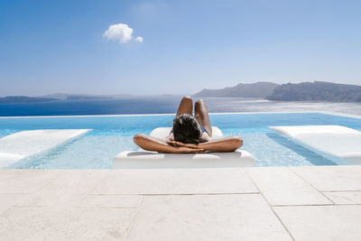Woman relaxing in swimming pool against sea