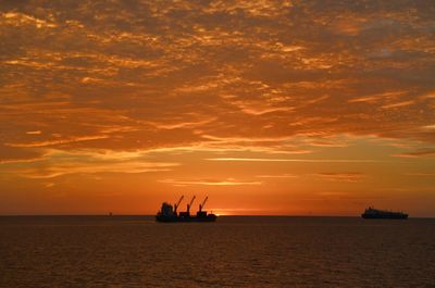 Silhouette ship in sea against sky during sunset