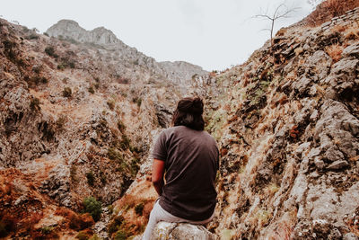 Rear view of man on rock in mountains