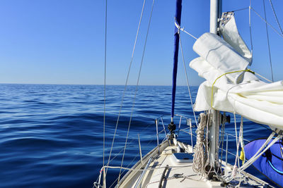 Sailboat sailing in sea against clear blue sky