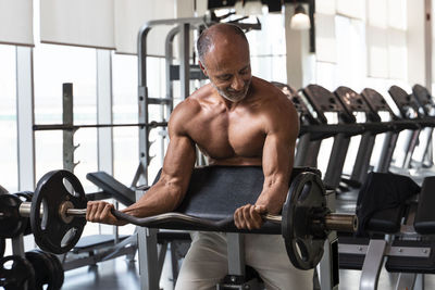 Shirtless man lifting weights in gym