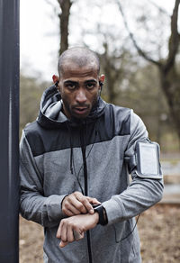 Portrait of confident male athlete wearing smart watch and arm band in forest