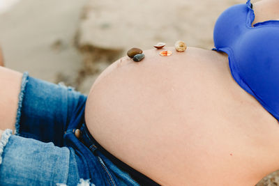 Midsection of pregnant woman at beach