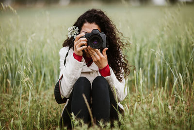 Woman photographing through camera on field