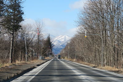 Empty road amidst trees against sky