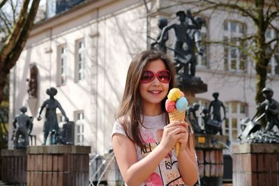 Portrait of happy girl having ice cream cone in city