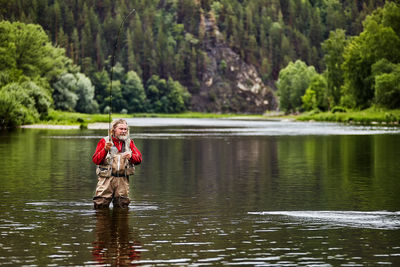 Portrait of smiling boy in lake against trees