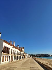 Street amidst buildings against clear blue sky