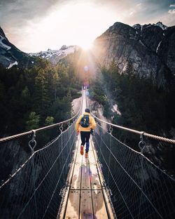 Rear view of man on footbridge against sky