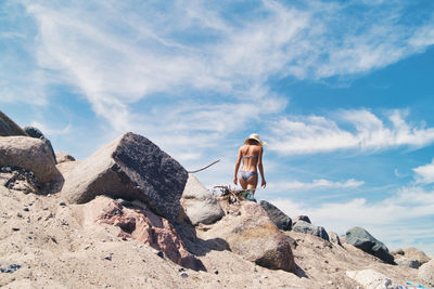 Man standing on rock against sky