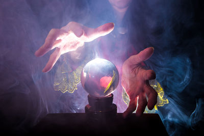 Midsection of female fortune teller by crystal ball