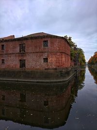 Reflection of building in river against sky