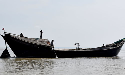 People on boat in sea against clear sky