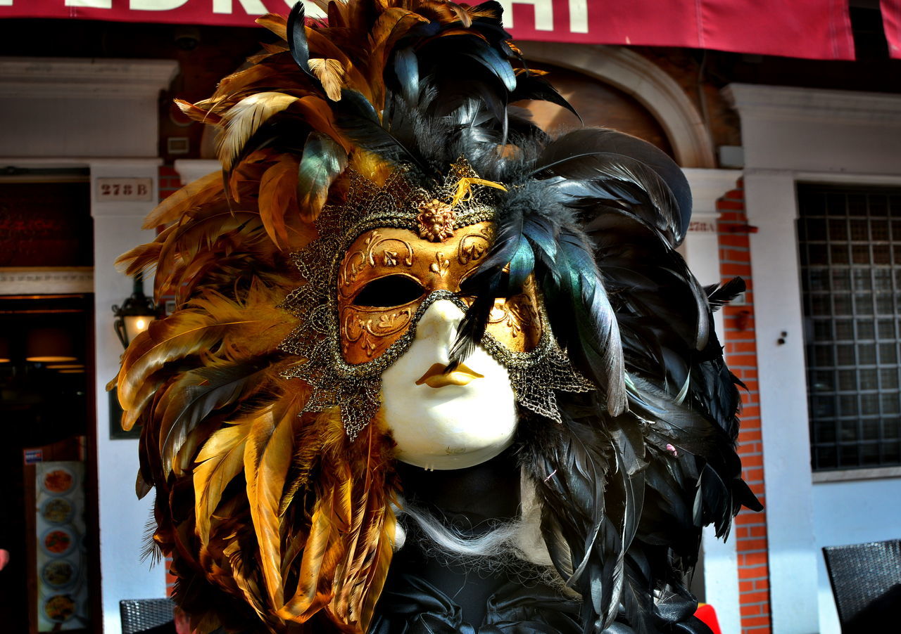 CLOSE-UP OF MASK WITH FEATHER AGAINST STAR SHAPE