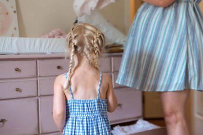 Rear view of girl standing with mother at home