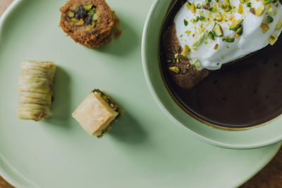 Hot chocolate drink in matching mint green cup and plate with assorted baklava desserts