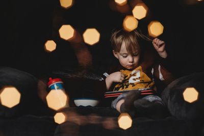Cute girl sitting in illuminated room