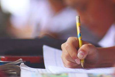 Cropped of hand of child writing on book on desk