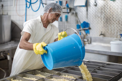 Cheese factory worker pouring curd into containers