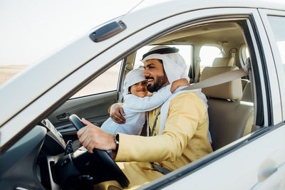 Father and son sitting in car at desert