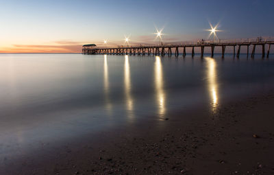 Pier over sea against sky during sunset